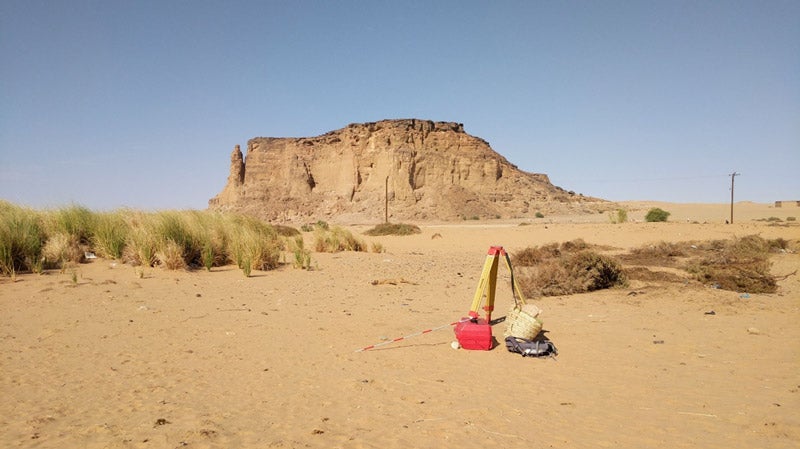 scientific equipment at base of rock outcrop in desert.