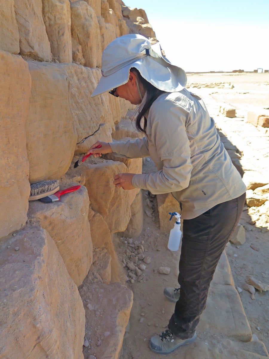 Woman brushing stone blocks of pyramid