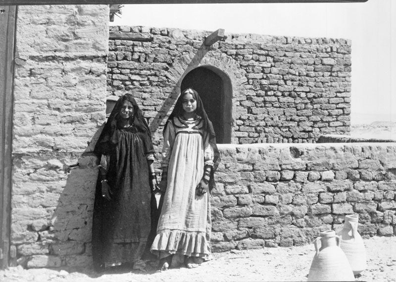 two young girls standing near a wall