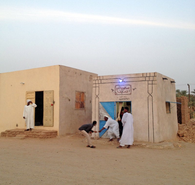 men in front of a low beige building in Sudan