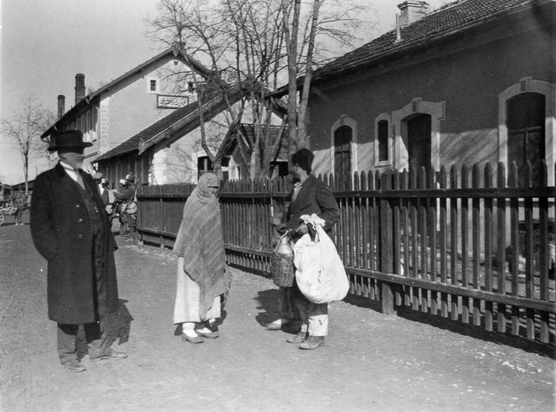 black and white photo of three people outside a train station.
