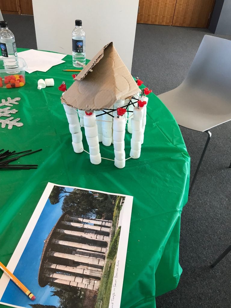 a photo of a structure rests next to a replica of the structure made of marshmallows on a table with a green tablecloth.