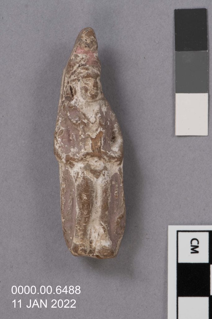 Painted terracotta figurine of Isis Aphrodite under visible light on a light gray background.