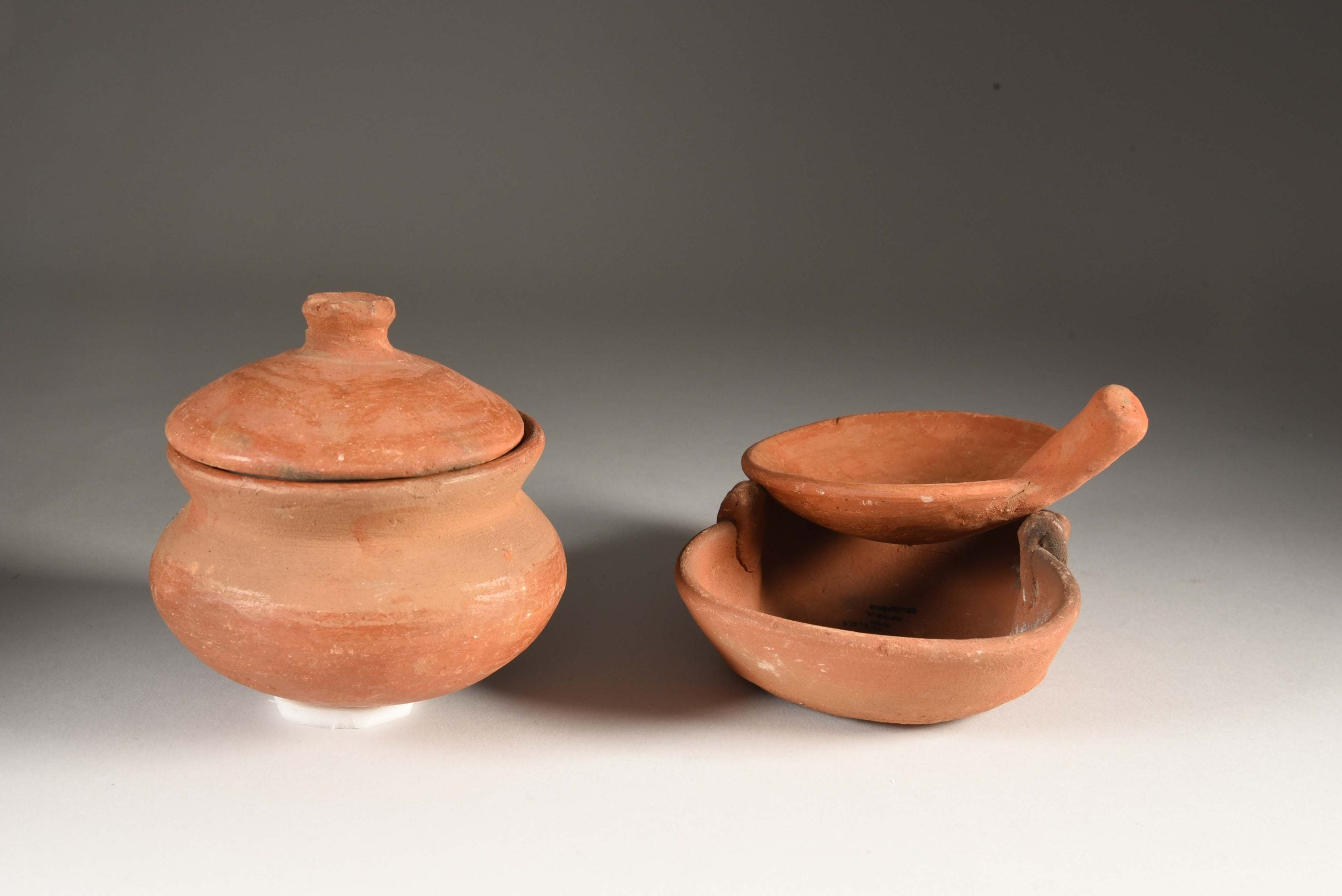 An image of a ceramic pot with a lid, and a frying pan on top of the ceramic stove.