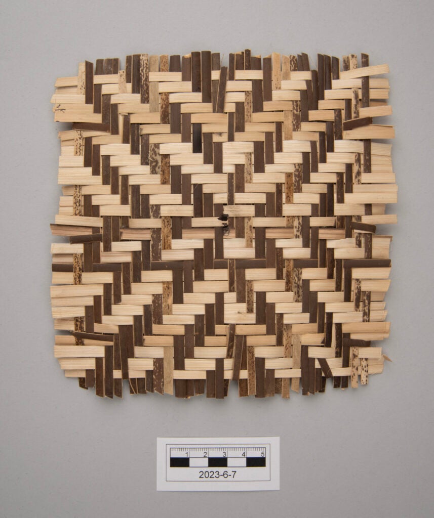 A square mat woven from light and dark reeds in a geometric pattern, exemplifying the art of Bontoc basketry, displayed on a gray background with a ruler and label reading 2023-6-7 below it for scale.
