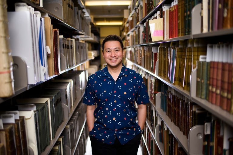 Ricky Punzalan stands in between long rows of library shelves