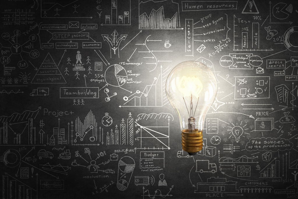 Light bulb shining in the middle of a blackboard full on ideas.
