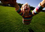 child swinging and laughing in a field