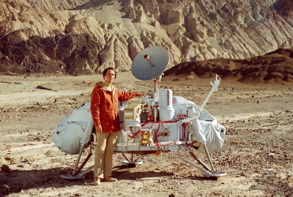 Dr. Carl Sagan poses with a model of the Viking lander in Death Valley, Calif.