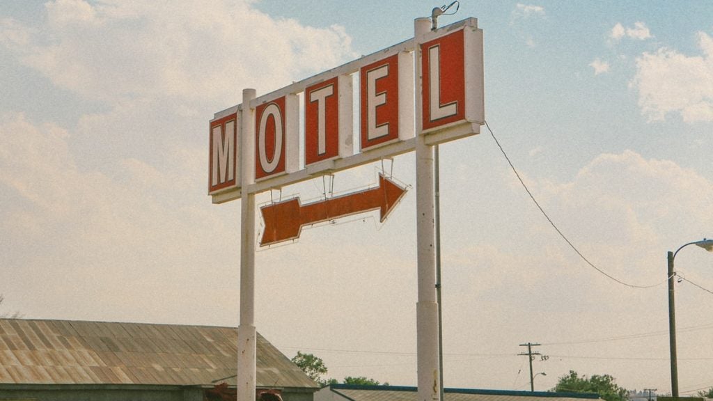 A motel sign with a red arrow against a faded blue sky