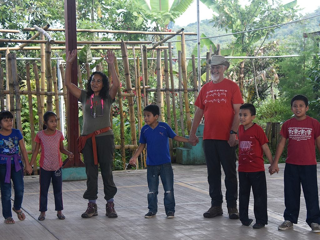 Ivette Perfecto (arms raised) and John Vandermeer play an ecological game with the children during Ecodía. Image credit this page: Jonno Morris.