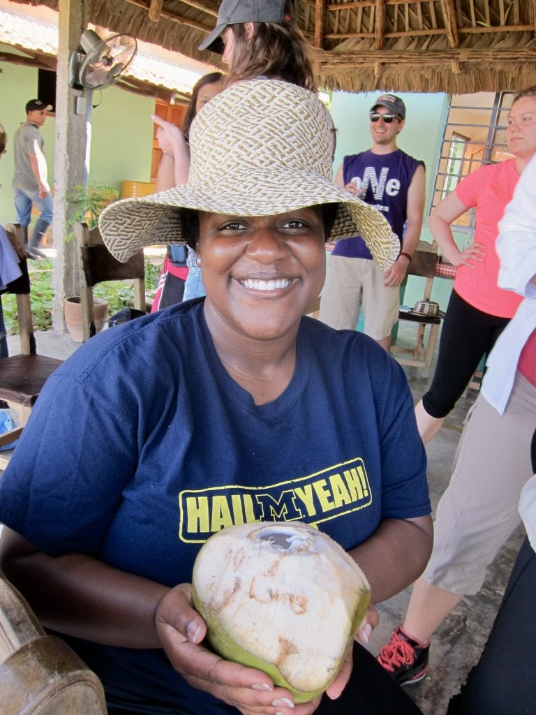 Student traveling abroad wearing a Michigan shirt and holding a coconut.