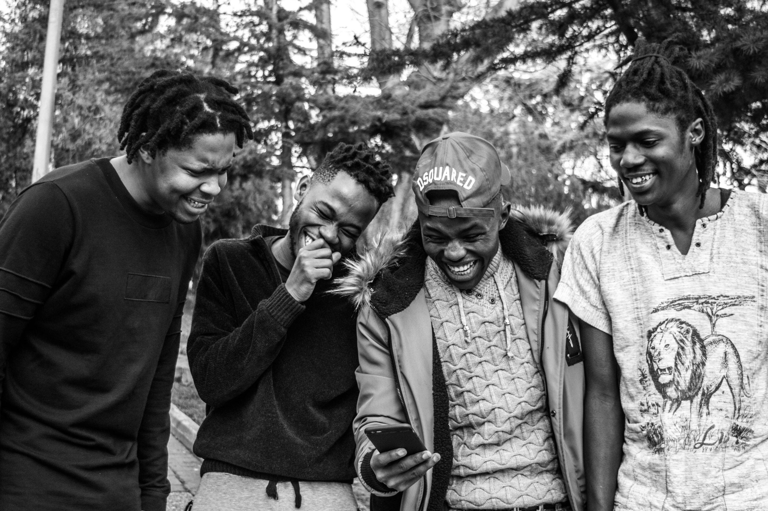 four young Black men laughing together