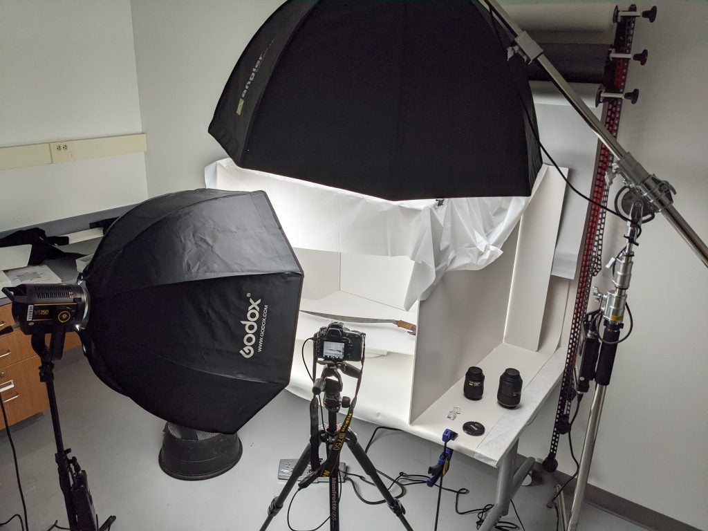Sword being photographed on table being lit by photo lights with large diffusers.
